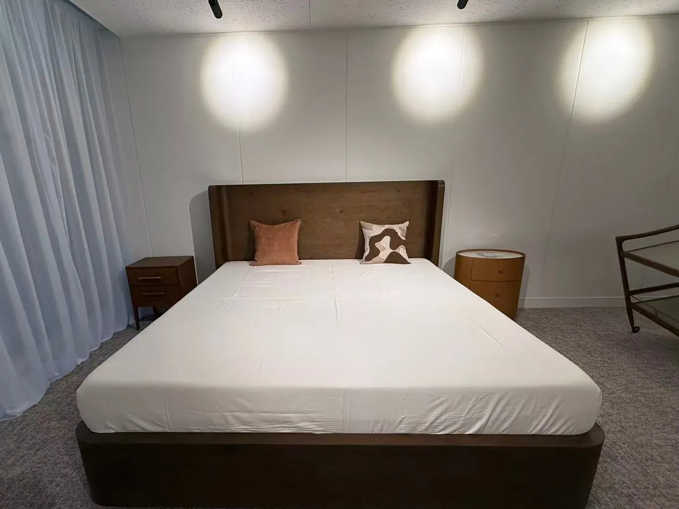 A bed with a tall wooden headboard between two bedside tables
