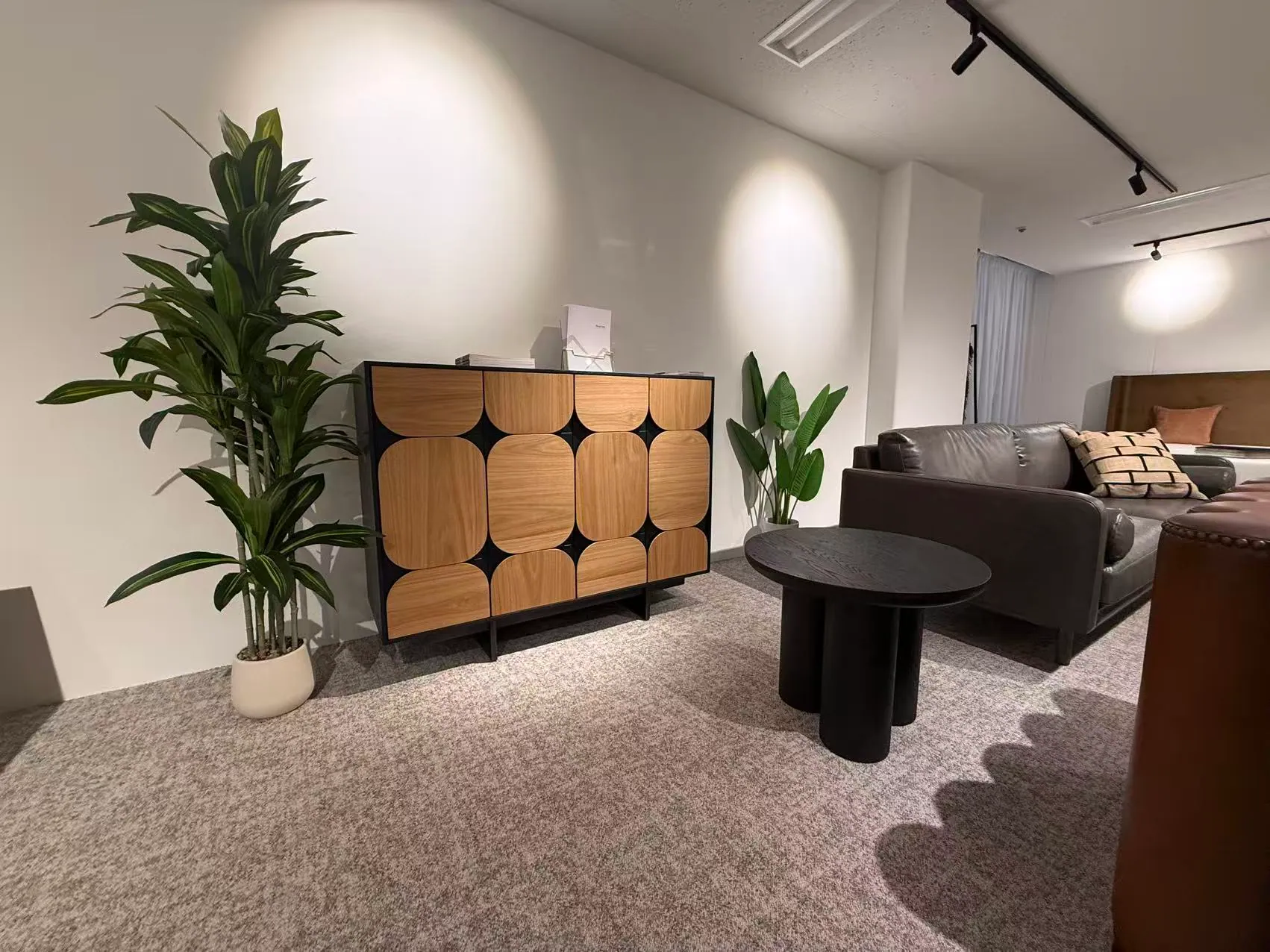 An oak sideboard with rounded panel doors, a round black side table and a leather sofa